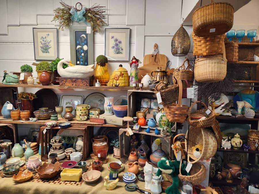 Shelves of pottery, baskets and framed botanical prints in a vendor booth