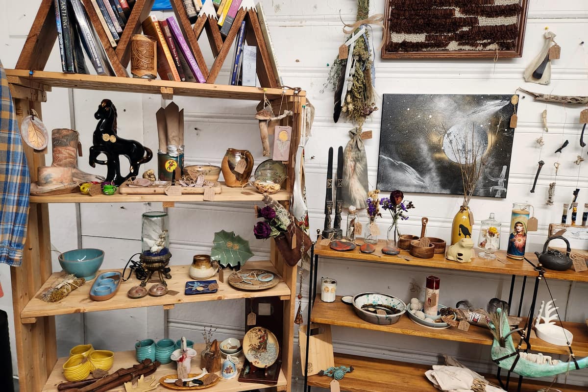 A vendor booth on the second floor at Thieves Market with handmade pottery, painted artwork and turned wood on open shelving
