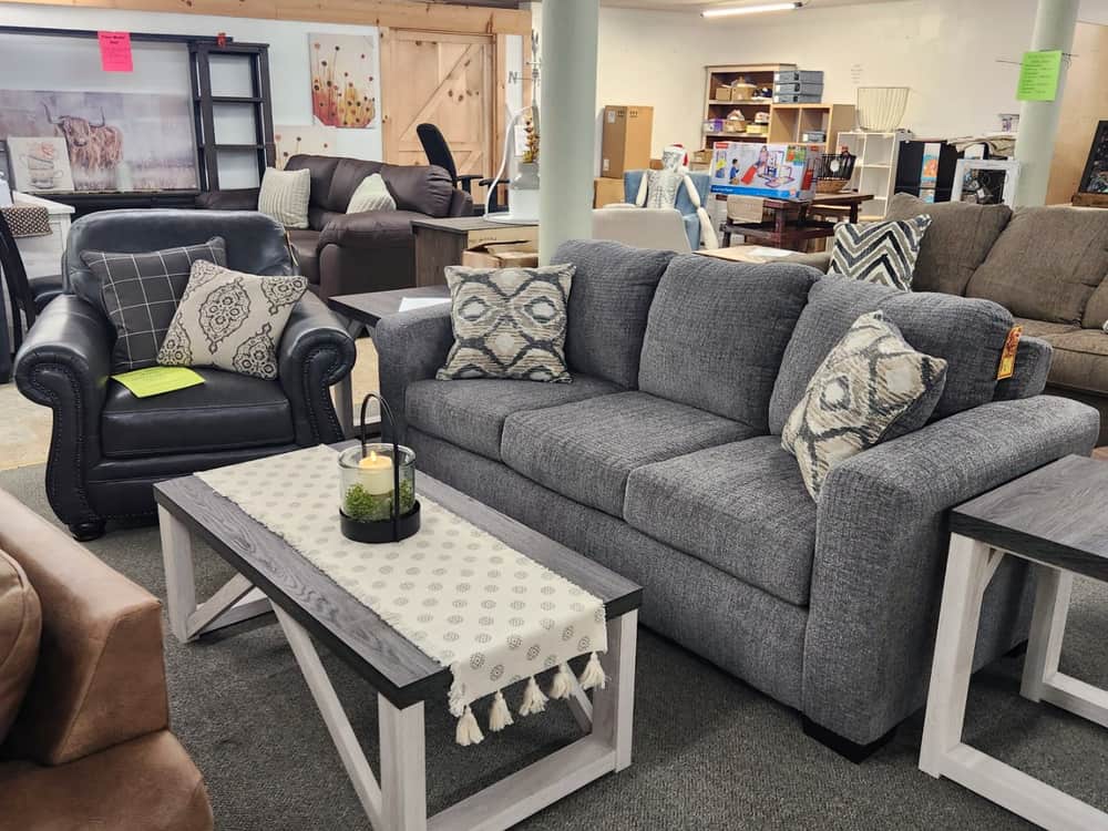 A grey sofa with a white and wood coffee table on the showroom floor