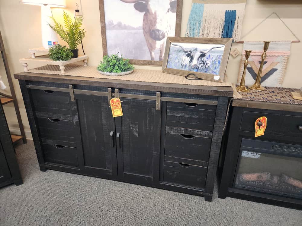 A black distressed sideboard with a sliding barn door and a warm brown top
