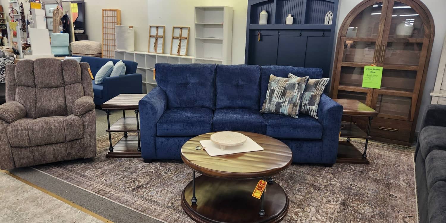 A navy sofa, a recliner and a round coffee table arranged on a rug at Thieves Market