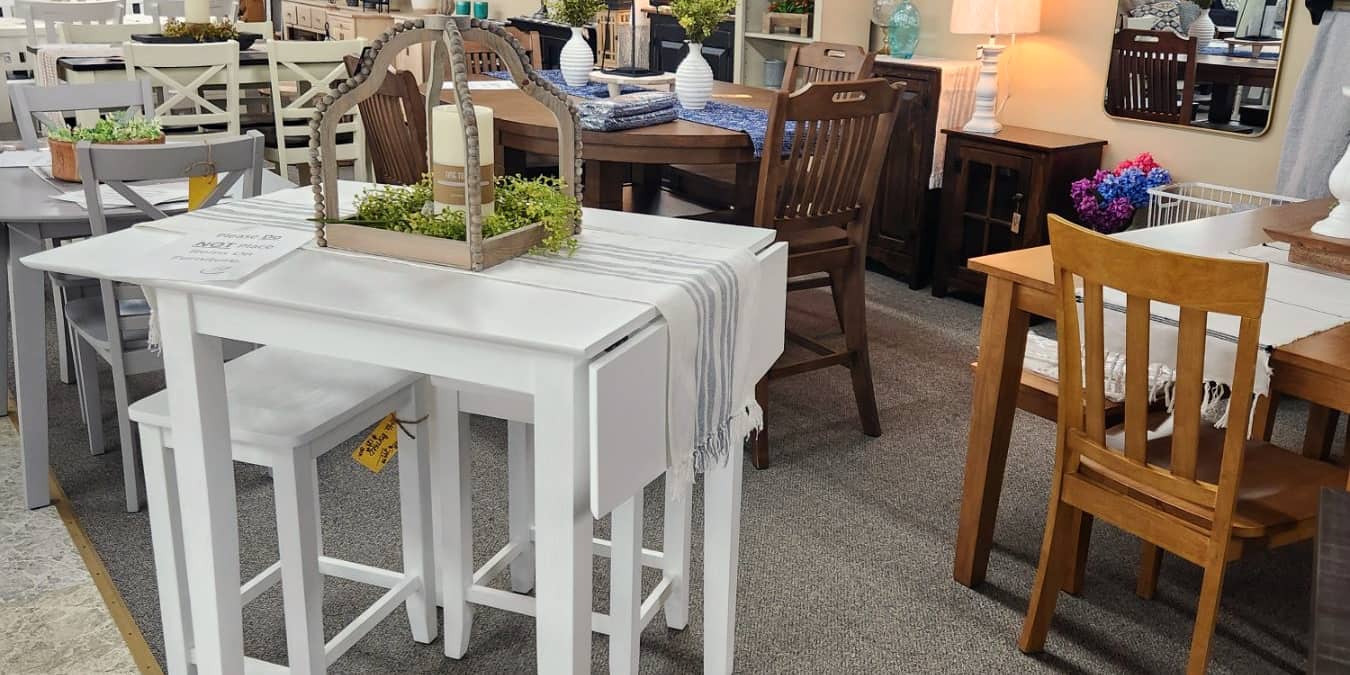 A white counter height table and stools among the dining sets at Thieves Market