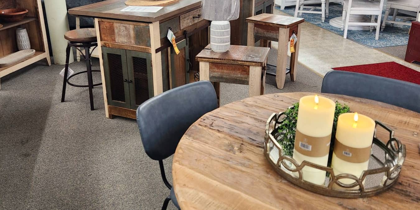 A round rustic wood table with navy chairs and three candles at Thieves Market