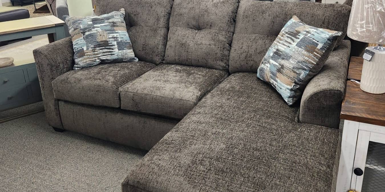 A taupe chenille chaise sectional with patterned cushions at Thieves Market