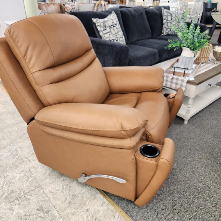 A grey upholstered rocker recliner beside a navy sofa