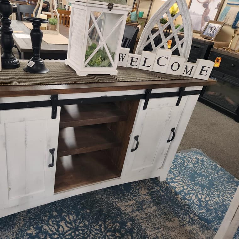 A white barn door television console with a brown wood top