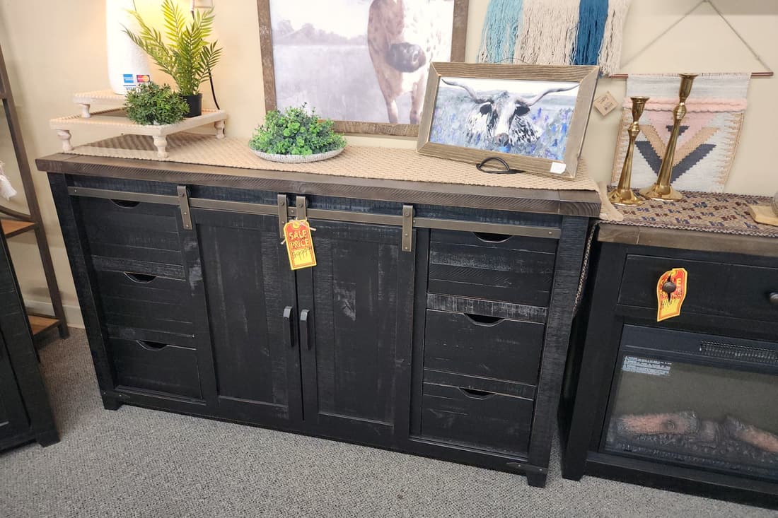 A black distressed sideboard with a sliding barn door and a warm brown top at Thieves Market