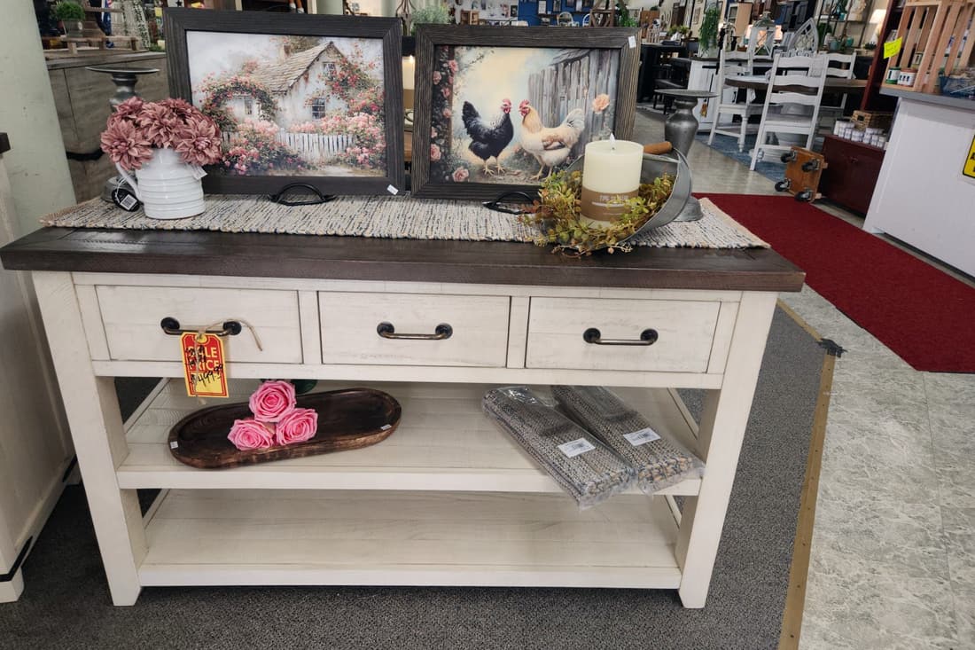 A cream console table with florals and framed art above it at Thieves Market